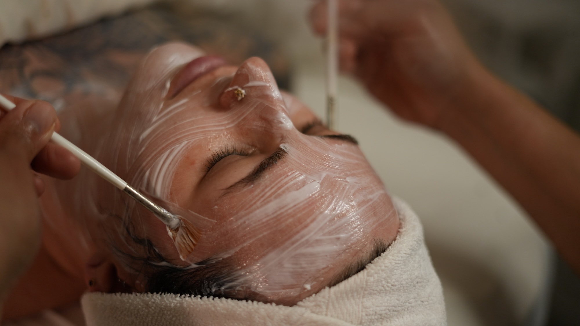 Close-up of a woman receiving a medical facial peel as the brushes go down her face.