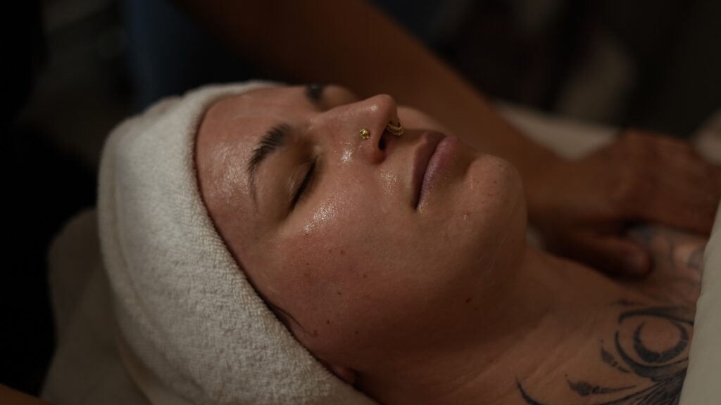 A female patient lays down with a spa headband around her head as she waits for her facial to treat acne, scarring, hyperpigmentation, melasma.