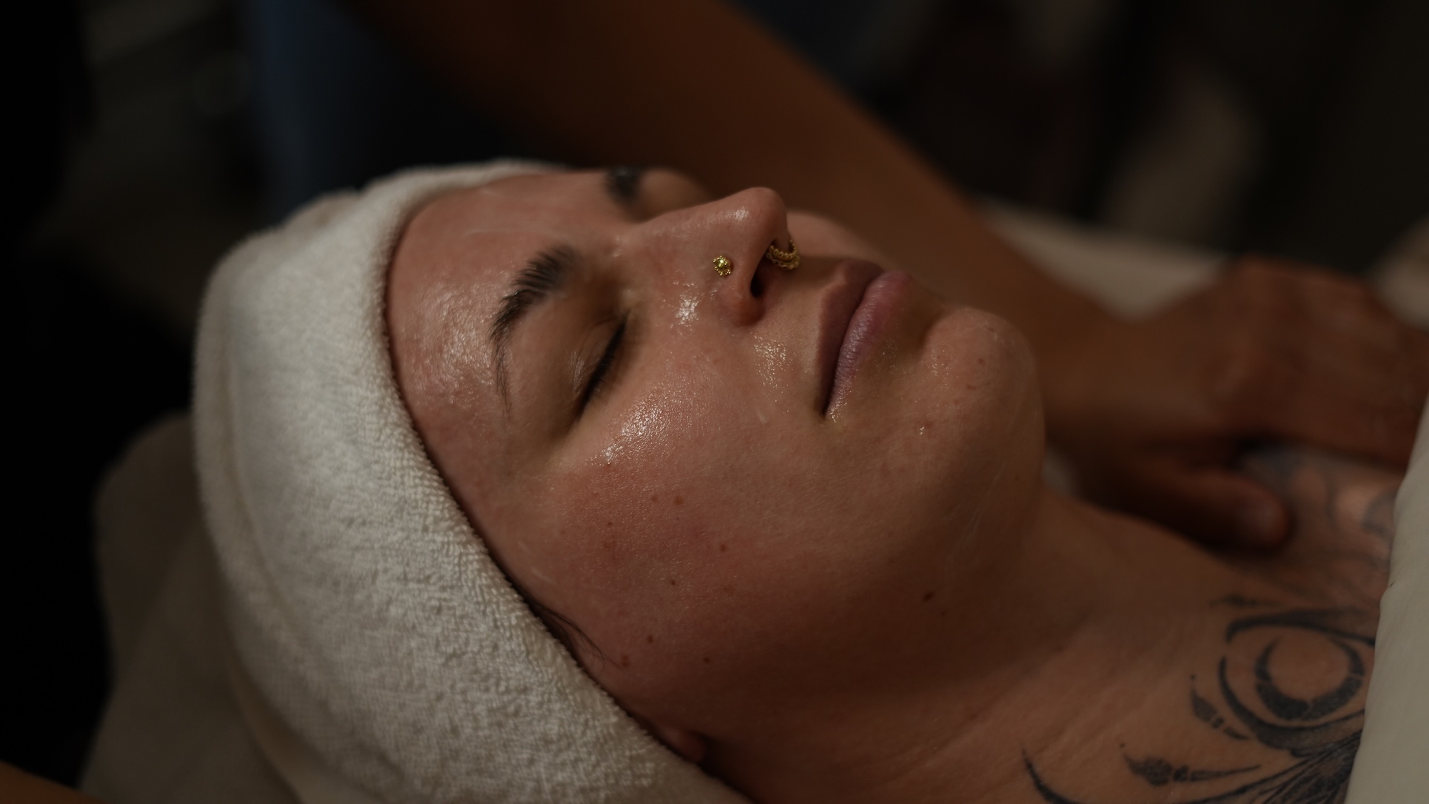 A female patient lays down with a spa headband around her head as she waits for her facial to treat acne, scarring, hyperpigmentation, melasma.