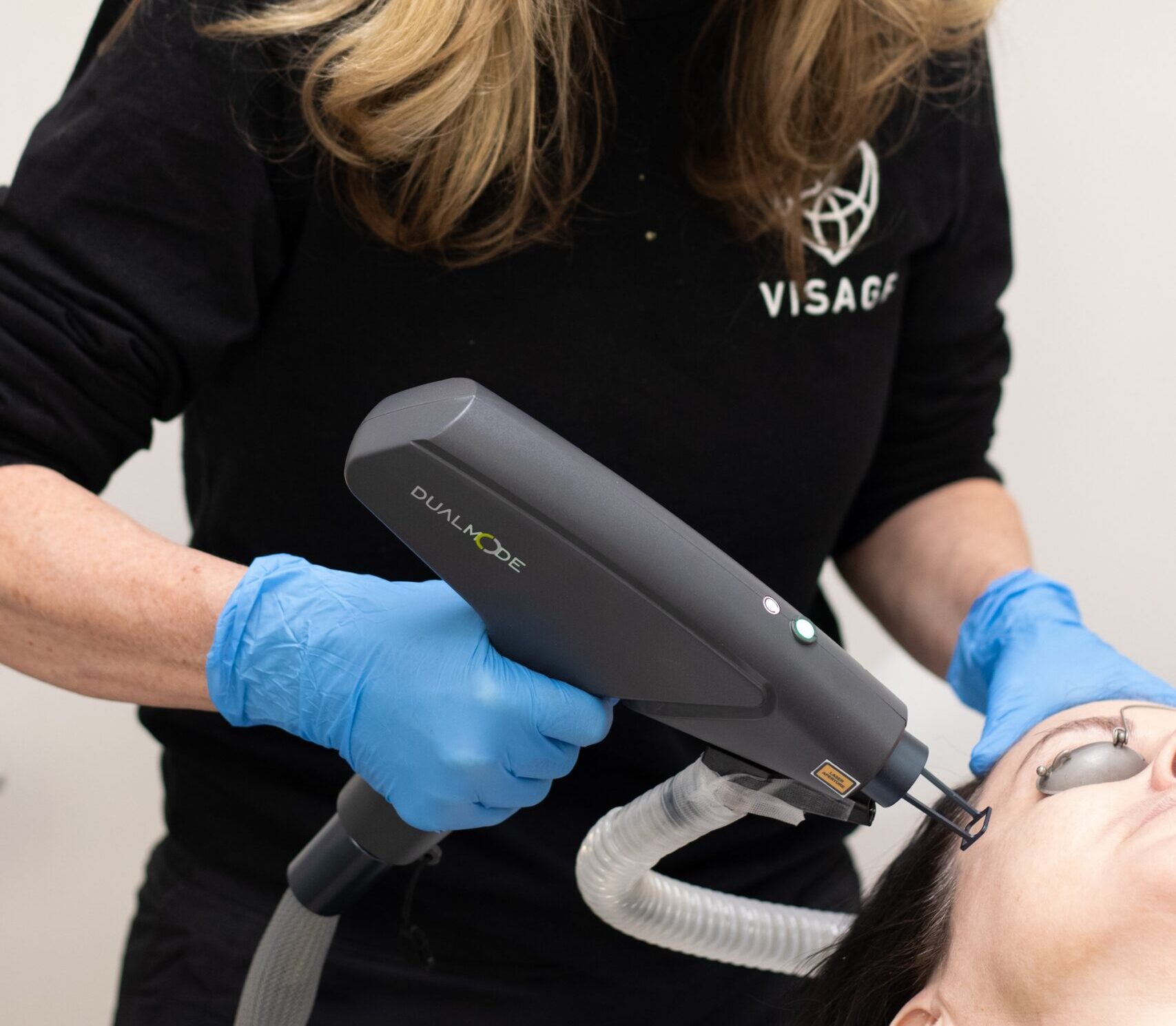 A female laser tech performs a light laser peel on a patient.