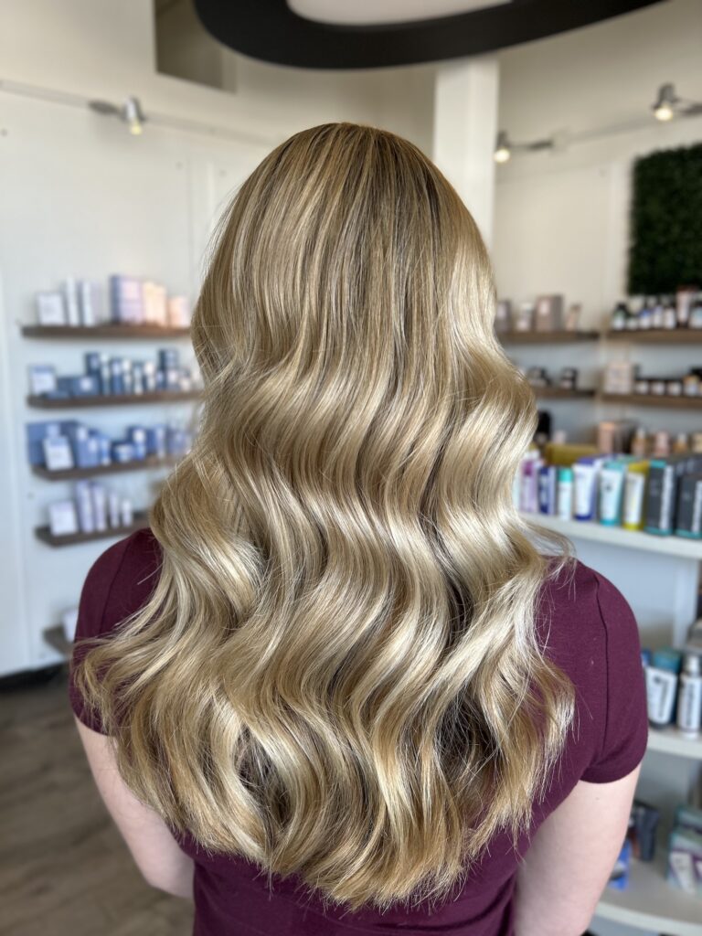 A woman with bleach blonde hair stands with her back to the camera.