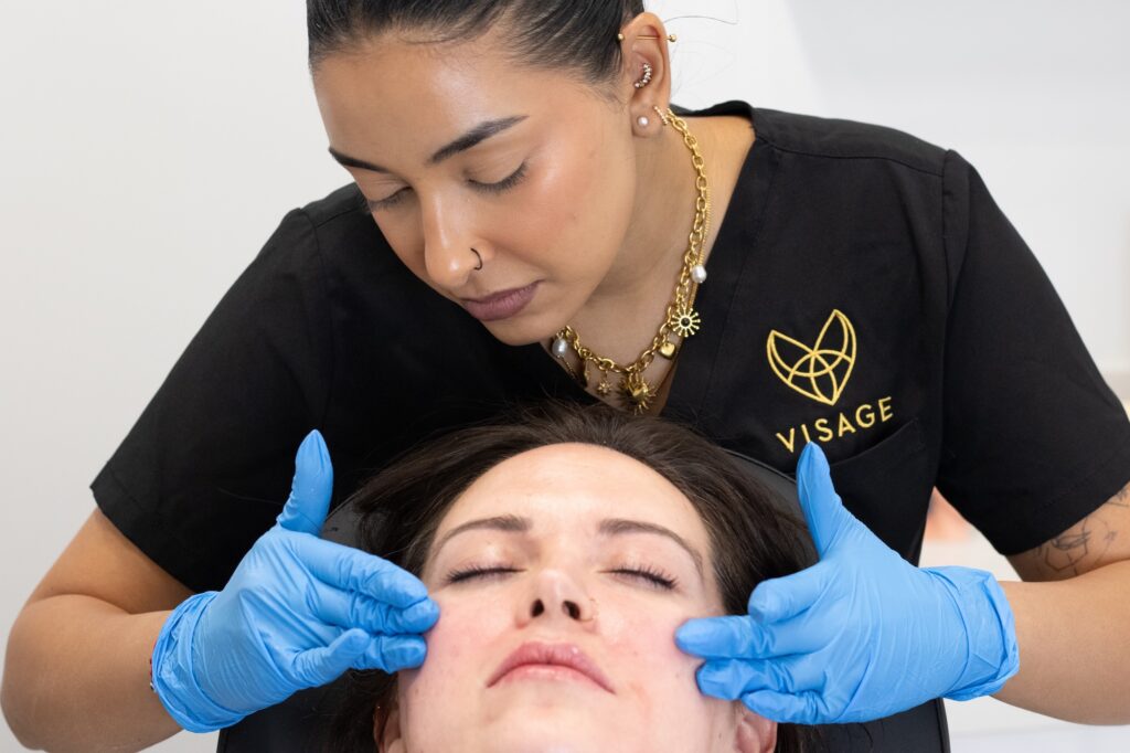A female nurse presses gently on a patients cheeks before a traditional aesthetics treatments