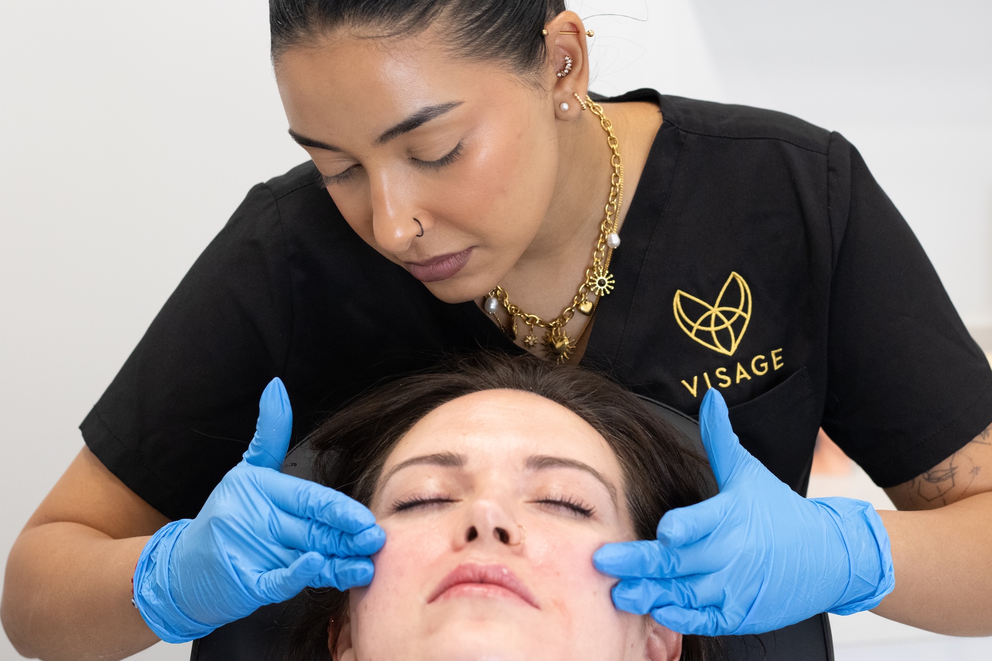 A female nurse presses gently on a patients cheeks before a traditional aesthetics treatments
