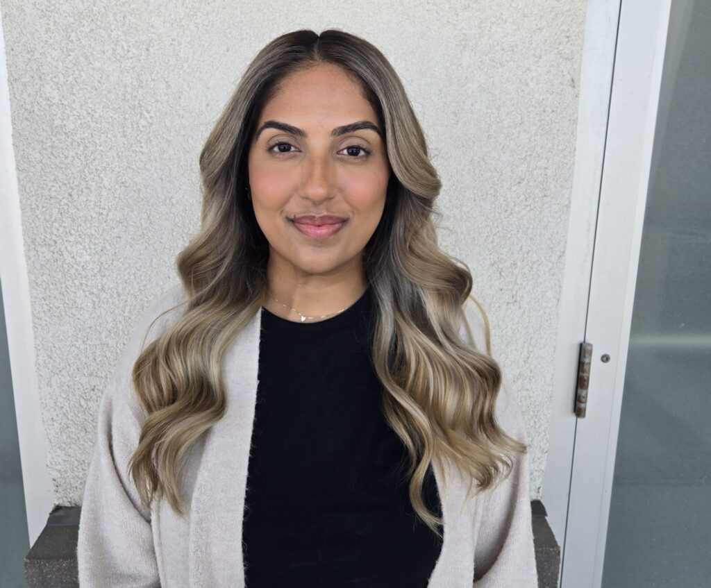 A girl with curly brown hair poses after getting a balayage in Winnipeg.
