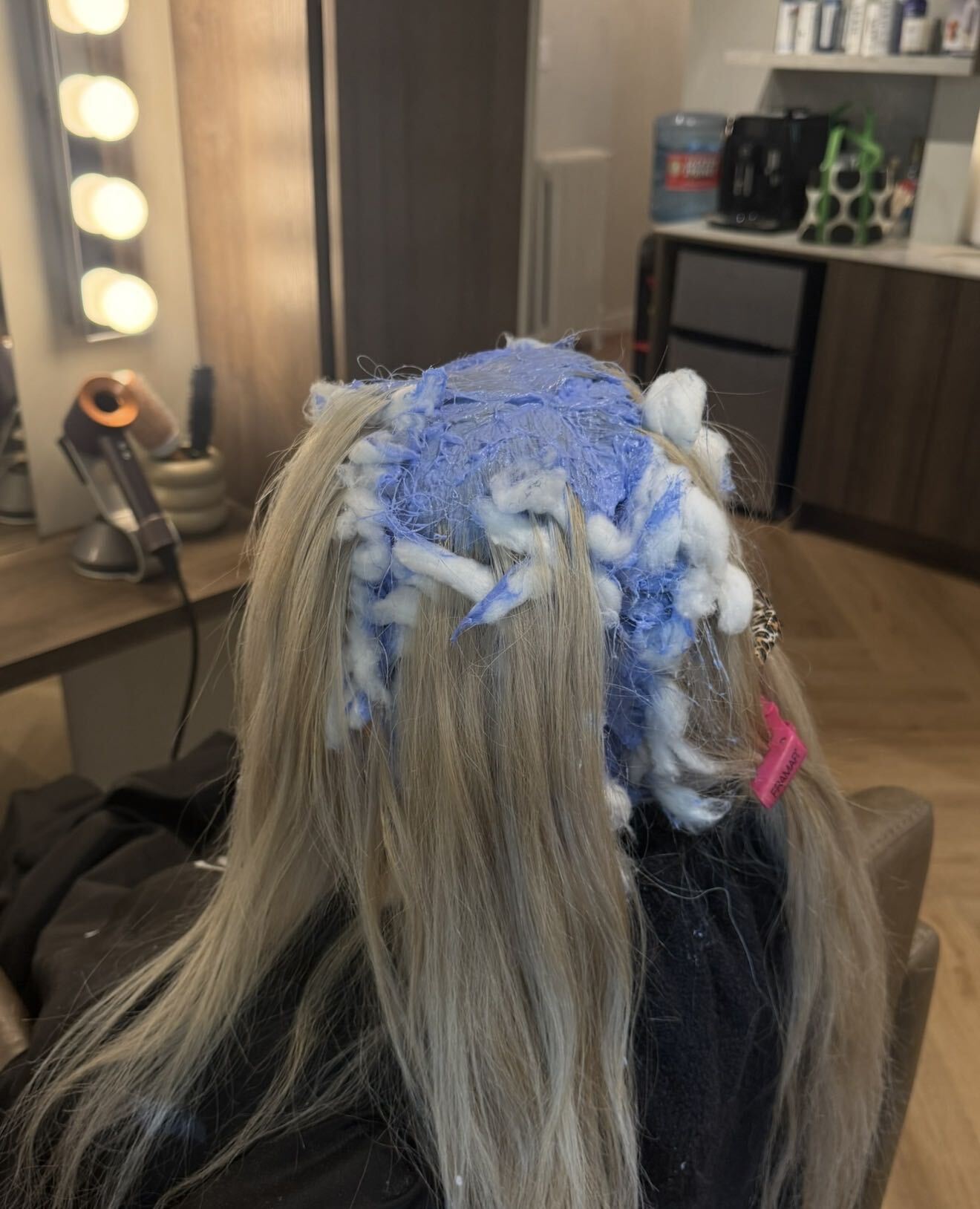 The back of a blonde woman's head as she receives a bleach blonde hair application in Winnipeg at Grace Hill Salon.